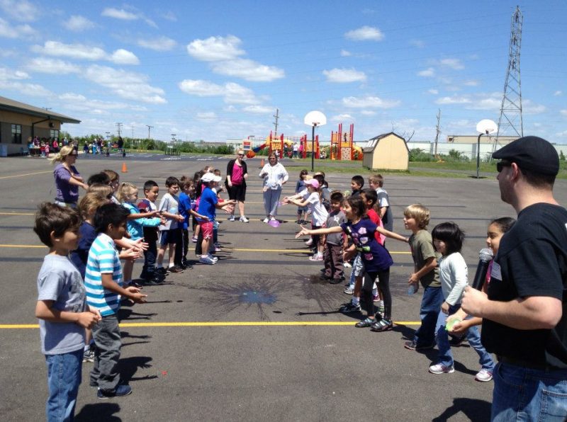 An interactive MC runs a water balloon toss at an elementary school field day